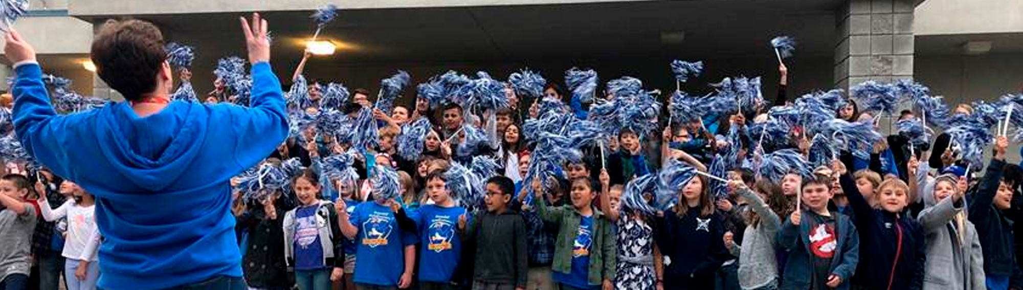 students and staff cheering and waving pom poms