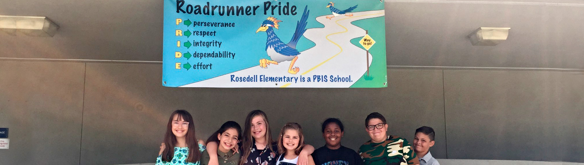 smiling students with a banner that says Roadrunner Pride. Perseverance, Respect, Integrity, Dependability, Effort. Rosedell Elementary is a PBIS School