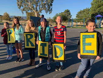 Students holding signs that spell out the word pride
